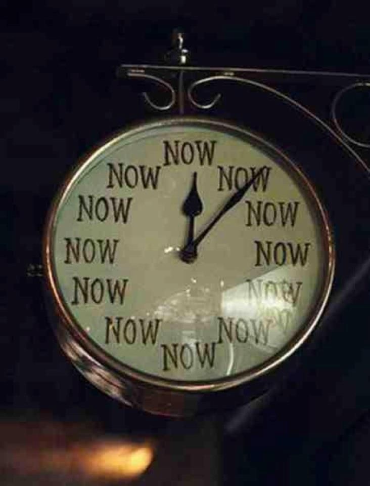 A round clock with all numbers replaced by the word "NOW" in black text—a playful reminder that self-awareness and personal growth begin in the present. The hour and minute hands point to "NOW," mounted on a decorative metal bracket.