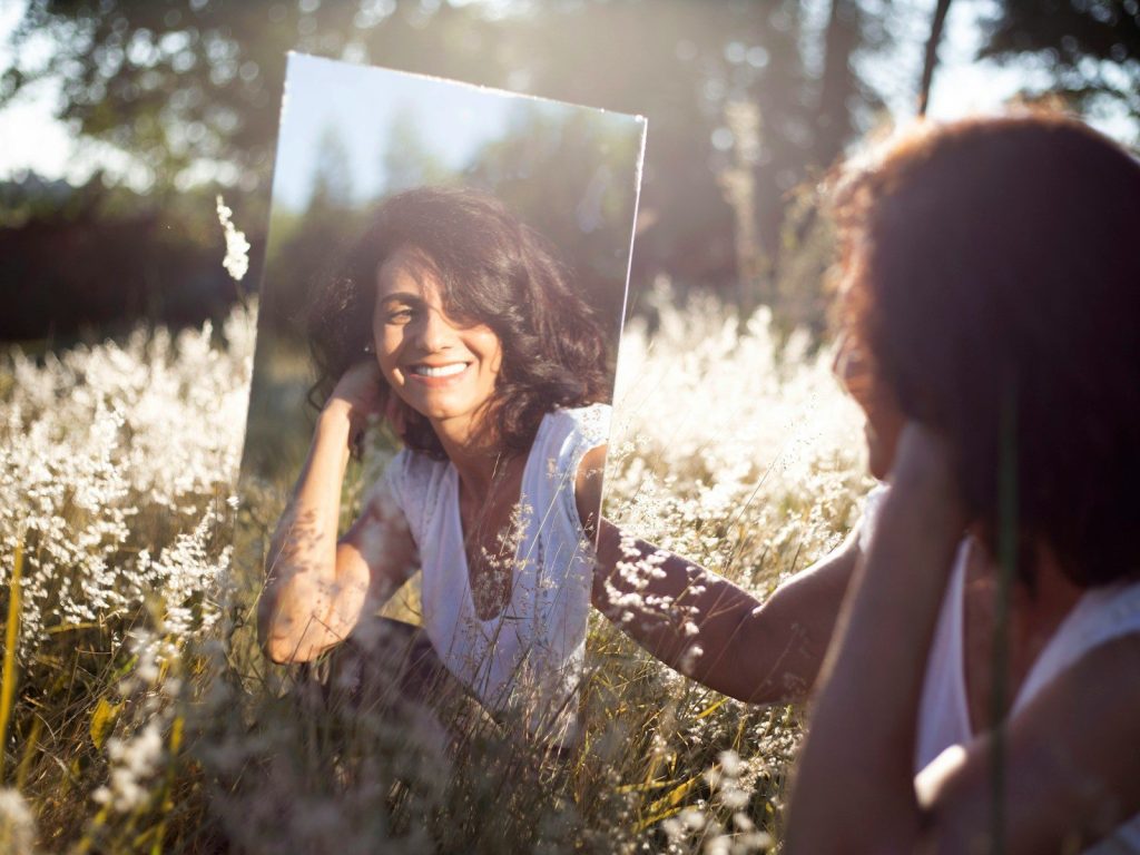 A person looking at their reflection with kindness rather than judgement.